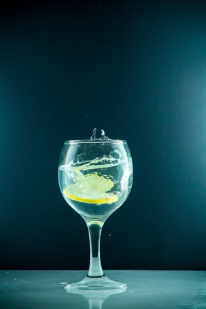 Glass glass of water with lemon on the isolated background. Mountain mineral pure mountain water with gas bubbles and a lemon slice and spray tonic refreshing sports drink.の写真素材