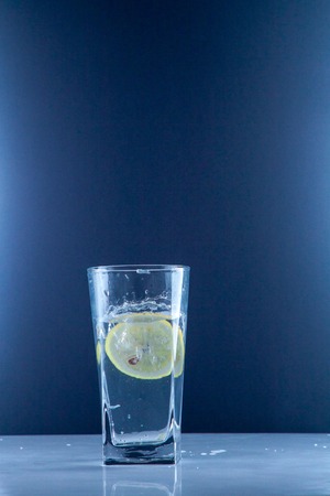 Glass glass of water with lemon on the isolated background. Mountain mineral pure mountain water with gas bubbles and a lemon slice and spray tonic refreshing sports drink.の写真素材