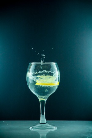 Glass glass of water with lemon on the isolated background. Mountain mineral pure mountain water with gas bubbles and a lemon slice and spray tonic refreshing sports drink.の写真素材