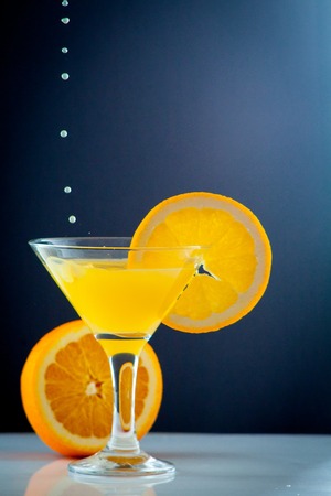 orange juice pouring into a glass with a slice of orange on a dark background beautifulの写真素材