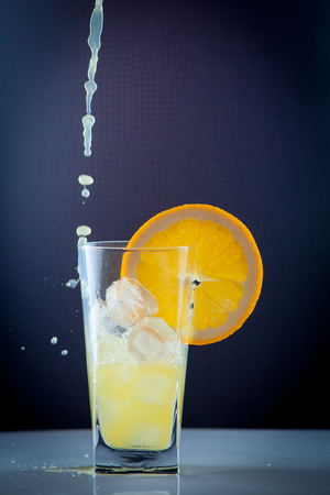 Isolated drink. Glass of orange juice and slices of orange fruit isolated on dark backgroundの写真素材