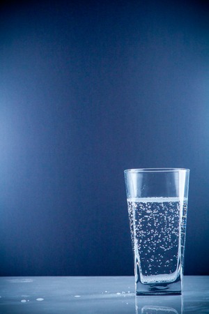 Pure mineral water pouring from a bottle into a glass. bottle of clear drinking cold mineral water with gas in isolation on the background next to a glass transparent glassの写真素材