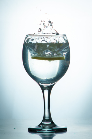 Glass glass of water with lemon on the isolated background. Mountain mineral pure mountain water with gas bubbles and a lemon slice and spray tonic refreshing sports drink.の写真素材
