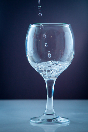 Clean drinking water from a source pouring into a clear glass beaker in the backgroundの写真素材