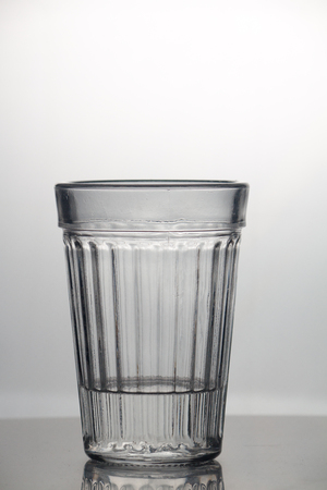 Transparent glass cup with a pouring bubbling cold fresh water with bubbles and dropsの写真素材