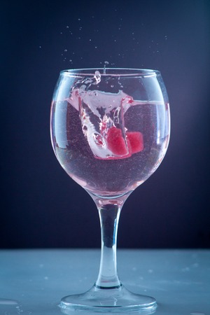 red heart of ice falling with splashes into a glass with a drink a cocktail of heartの写真素材