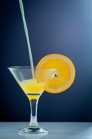 Isolated drink. Glass of orange juice and slices of orange fruit isolated on dark backgroundの写真素材