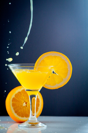 Isolated drink. Glass of orange juice and slices of orange fruit isolated on dark backgroundの写真素材