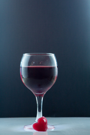 bright beautiful red wine pouring jet into a transparent glass cup isolated on a dark backgroundの写真素材