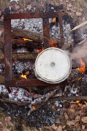 metal pot with a meal basking on burning firewood in the forest wildlifeの写真素材