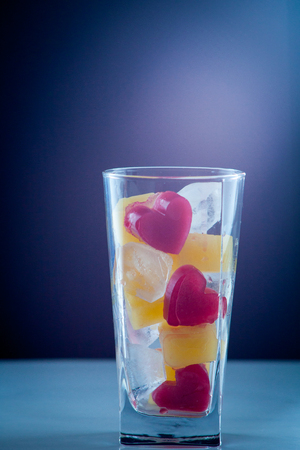 red heart of ice falling with splashes into a glass with a drink a cocktail of heartの写真素材