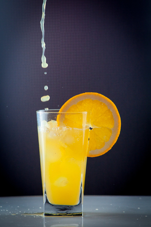 Isolated drink. Glass of orange juice and slices of orange fruit isolated on dark backgroundの写真素材