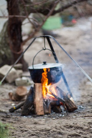 metal pot with a meal basking blured on burning firewood in the forest wildlifeの写真素材