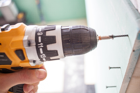 interior house alterations works Drywall Construction worker holding the hand drill electric screwdriverの写真素材