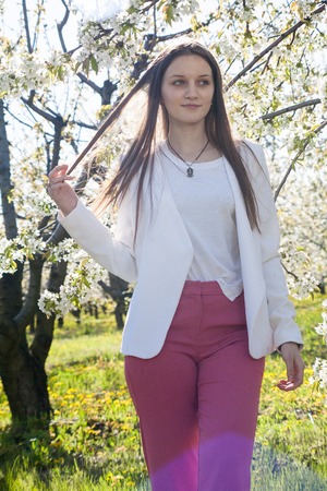 Portrait of a beautiful young girl in a blooming garden against a background of flowering trees on a...
