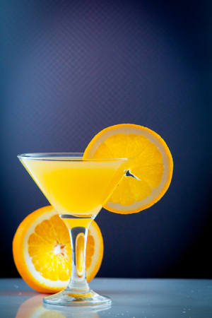 Isolated drink. Glass of orange juice and slices of orange fruit isolated on dark backgroundの写真素材