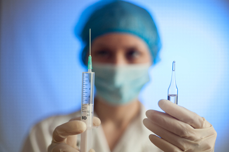 Syringe, medical injection in hand, palm or fingers. Medicine plastic vaccination equipment with needle. Nurse or doctor. Liquid drug or narcotic. Health care in hospital.の写真素材