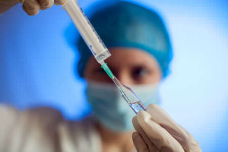 Syringe, medical injection in hand, palm or fingers. Medicine plastic vaccination equipment with needle. Nurse or doctor. Liquid drug or narcotic. Health care in hospital.の写真素材