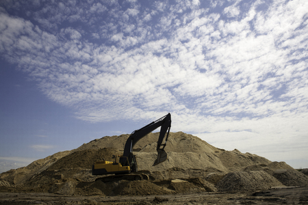 A large yellow excavator on the road construction site picks up and pours sand rubble stones in a quarry construction machinery excavator digsの写真素材
