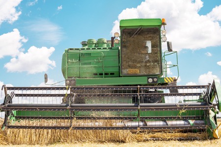 Combine machine is harvesting oats on farm field. combine harvester working on a wheat field. Combine harvester cuts the field of mature ripe yellow wheatの写真素材