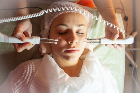 electrostimulation myostimulation under stress with rejuvenation and ultrasonic skin cleansing for a young girl in a spa salon stimulating the skin with microcurrentsの写真素材