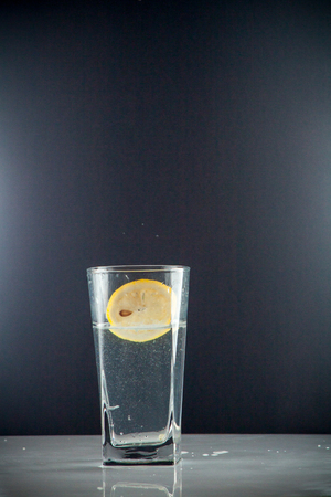 Glass glass of water with lemon on the isolated background. Mountain mineral pure mountain water with gas bubbles and a lemon slice and spray tonic refreshing sports drink.の写真素材