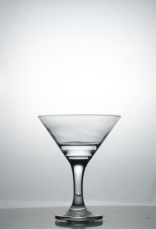 Transparent glass cup with a pouring bubbling cold fresh water with bubbles and dropsの写真素材
