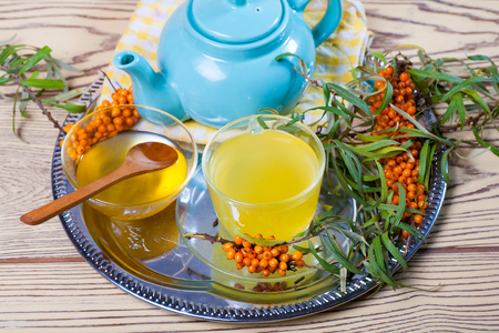 Tea made from sea buckthorn berries healthy for health delicious, saturated with vitamins surrounded by berries and sea buckthorn leaves for family tea drinking and maintaining health in the bodyの写真素材