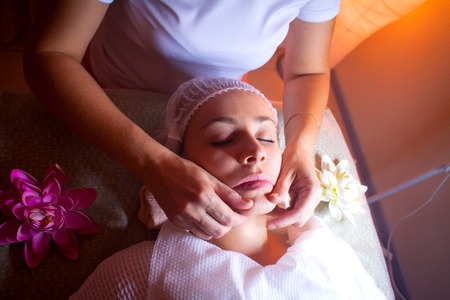 Massage of the lips of a young girl with a special master proffesionalom hands in the SPA salon cleansing of the skin facial massageの写真素材