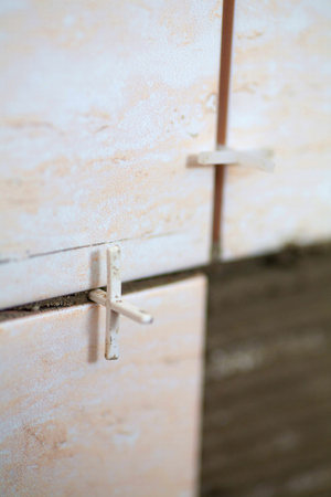 laying of tiles industrial construction worker installing small ceramic tiles on bathroom walls and applying mortar with trowelの写真素材