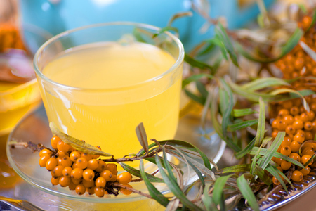 Healing sea-buckthorn tea delicious aromatic full of vitamin and microelements of bright yellow color with berries and leaves of the sea buckthorn fruit on a white background.の写真素材