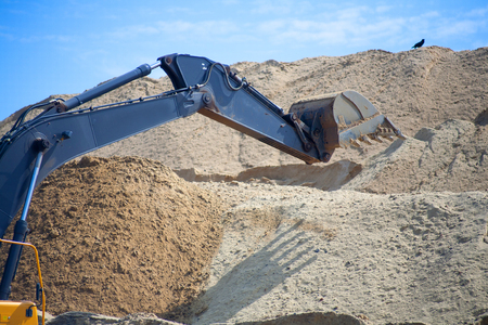 A large iron excavator bucket collects and pours sand rubble and stones in a quarry at the...