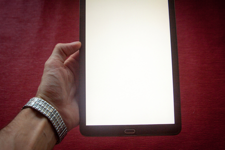 Office worker businessman holding a digital tablet with a white screen working online in the office at the tableの写真素材
