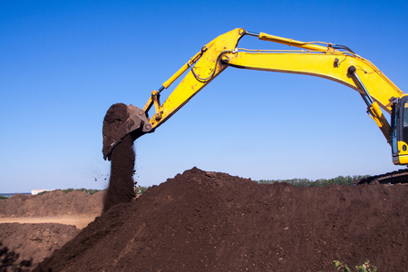 A large construction excavator of yellow color on the construction site in a quarry for quarrying