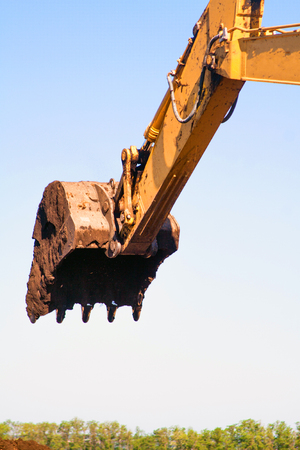 Close-up of a bucket of a construction excavator. A large detail of a construction machine of a yellow color digs up a crutch and pours it.の写真素材