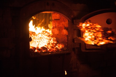 Throw more charcoal on the fire in open iron stove boiler-houseの写真素材