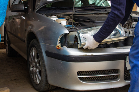 Mechanic in autoservice installing a headlamp to a car. car headlight repair. background image for auto service article.の写真素材