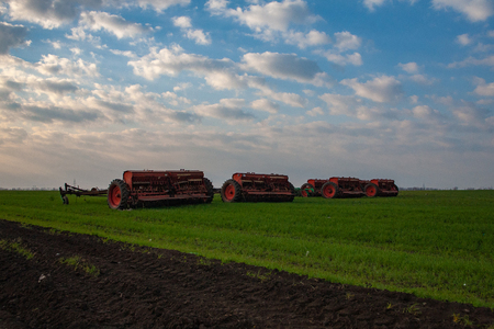 seeders work in the field on the ground in the spring. The mechanization of modern agriculture agricultural machines. Spring field work on farmlands.の写真素材