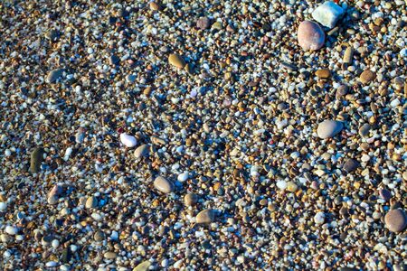 sea pebbles colored granite on the beach background stones. The shore of the beach with sand and...