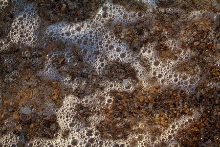 sea pebbles colored granite on the beach background stones. The shore of the beach with sand and...