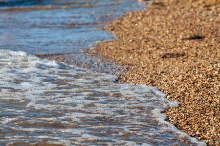 sea pebbles colored granite on the beach background stones. The shore of the beach with sand and...