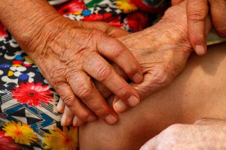 Elderly husband and wife hold hands with love. Grandparents hold each other's hands. Retirees in a...