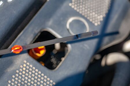 A mechanic checks the oil level in a car engine when servicing a car under an insurance warranty at...