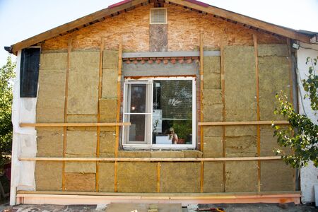 warming the walls of a stone house with a stone wool heater. Ecological insulation of rooms with building a house. Installation of cellulose thermal insulation in the wall of the frame houseの写真素材