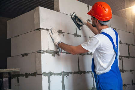 Master foreman puts a wall of aerated concrete blocks when building a house. Private housing...