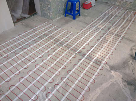 Closeup of concrete and red electrical wires. Electric floor heating system installation in new house. Closeup of concrete and red electrical wiresの写真素材