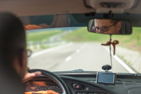 driver behind the wheel of a car in the mountains, perspective view. Driver with hands on the steering wheel. Traveling by car along a mountain road.の写真素材