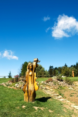 Wooden sculptures in the meadow in front of trees on the hill Solan, Moravian Beskydy Mountains Czech Republic   の写真素材