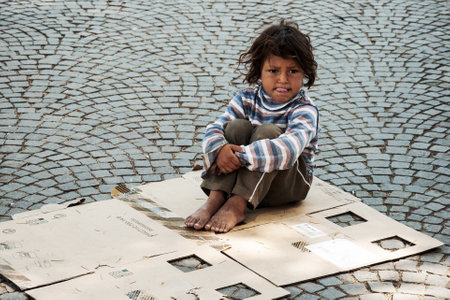 TIRANA, ALBANIA, MAY 14, 2010 - Unknown homeless kid sitting on the old box on the street in Tiranaのeditorial素材
