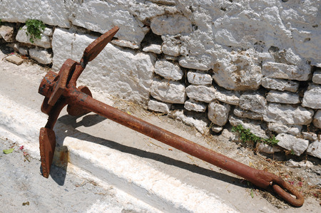 Old rusty ship anchor at the wall of the house in Greek streetの写真素材